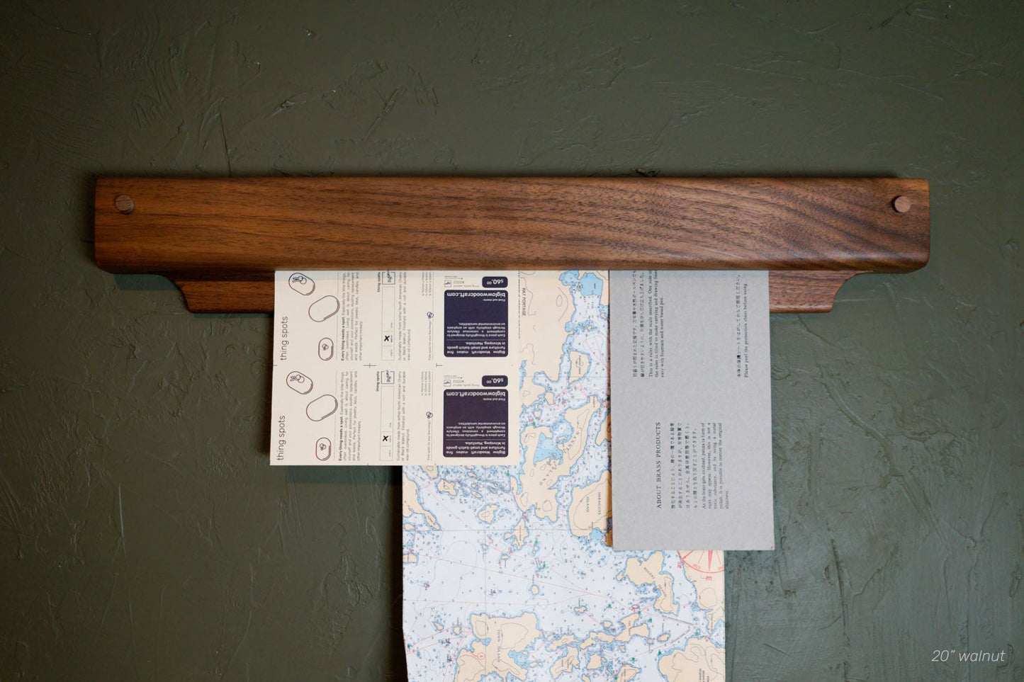 The Gravity Bar, by Biglow Woodcraft; a wooden holder for papers, pictures and images. A wooden bar installed on a green wall, holding documents. Hardwood Walnut