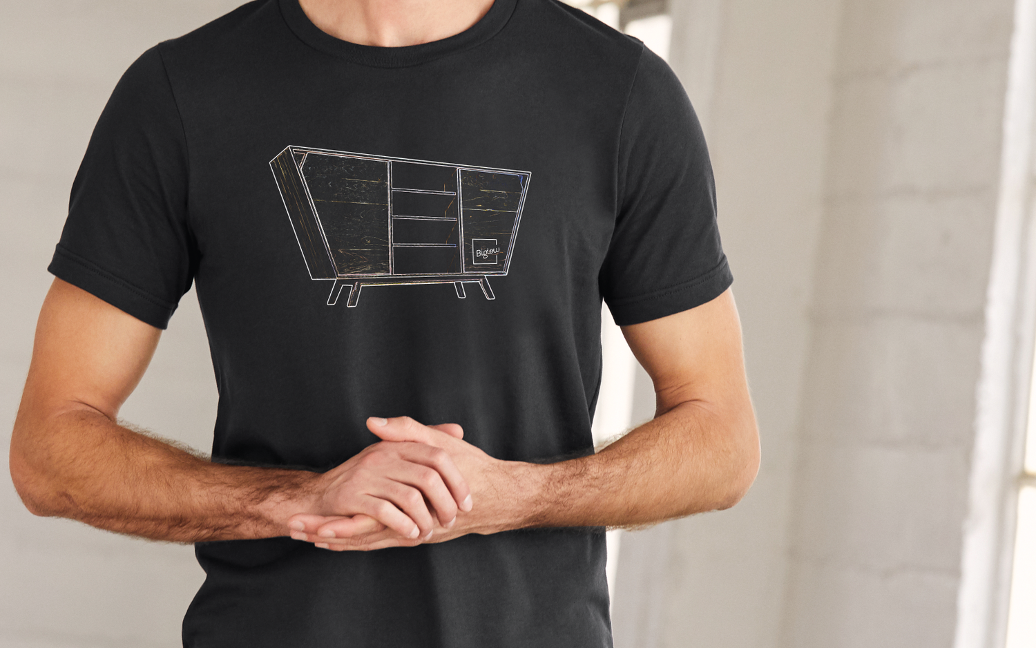 A black shirt on a male with a custom fine furniture piece on the front in line art.