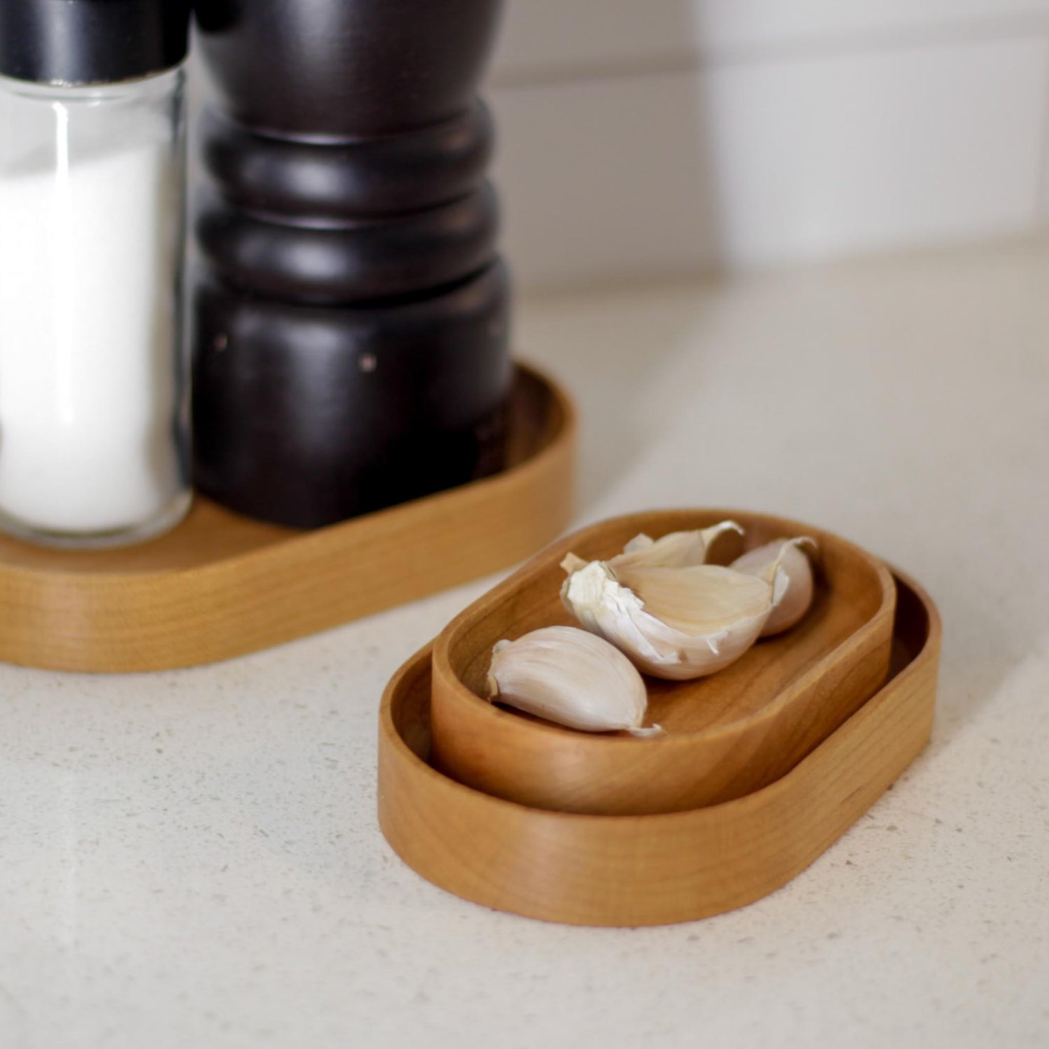 The Thing Spots, by Biglow Woodcraft; a wooden tray for small objects. A Thing spots with garlic, salt and pepper on a white kitchen countertop. Hardwood Red oak