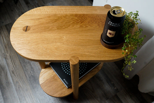 The Beside Table, by Biglow Woodcraft; a wooden table with a beer, a plant and a book. Hardwood White Oak