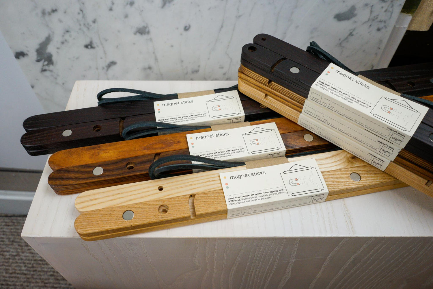 The Magnet Sticks, by Biglow Woodcraft; a wooden support for papers, photographs and images. Various sets of magnet sticks on a white table. Hardwood