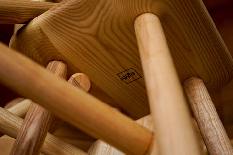 A closeup of the underside of one of the children's chairs from a custom children's dining set. The Biglow Woodcraft logo is burned into the wood and in focus.