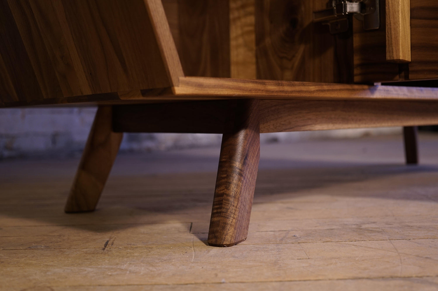 A close up of the mid-century modern style feet of a custom walnut cabinet.