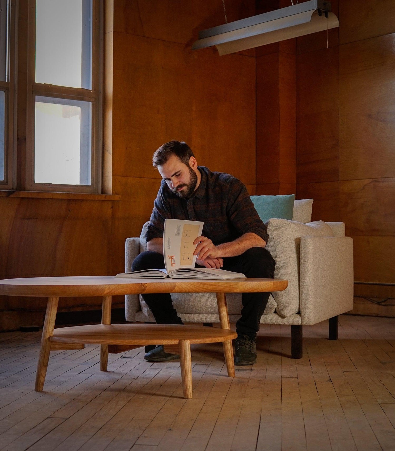 Brent Biglow reading a Hans Wegner book at a custom coffee table he designed and built.