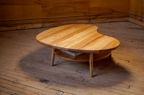 A mid century style custom coffee table with dramatic lighting. Made from solid White Ash in Winnipeg, with a Hans Wegner design book sitting on it's lower shelf.