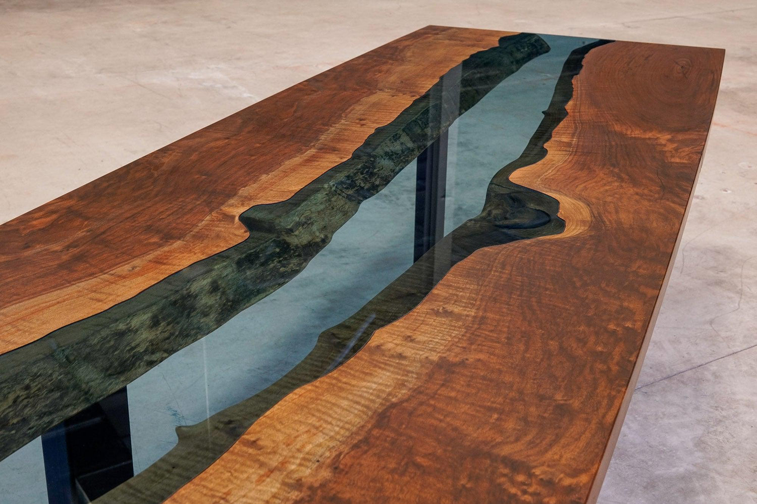 A top down view of a glass inlaid river table, made from large pieces of walnut and a custom piece of tempered glass.