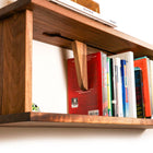Close‑up of sliding book stop gripping row of books on walnut shelf | Biglow Woodcraft