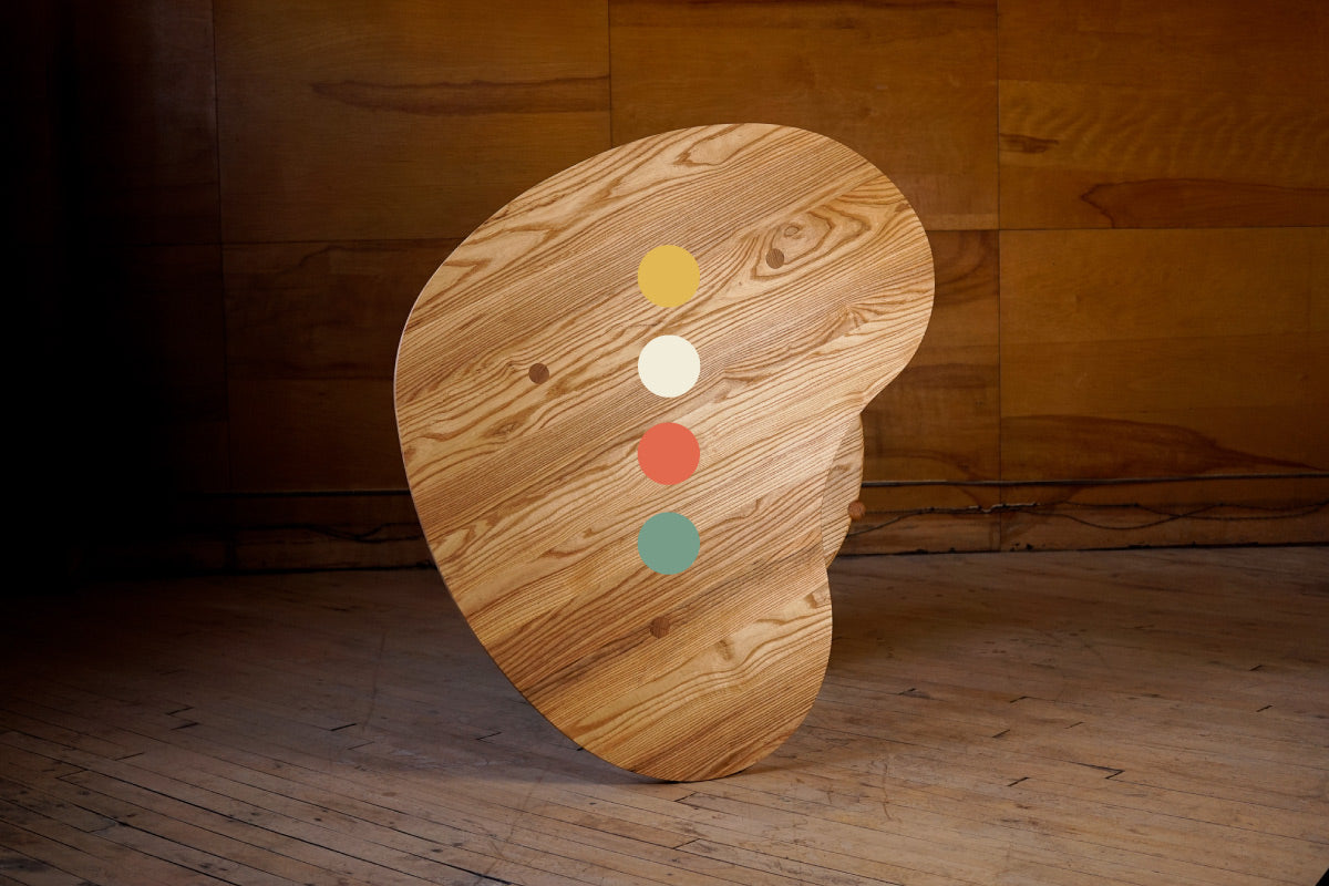 A design centric hardwood coffee table with the Biglow Woodcraft "dots" logo superimposed on the front.