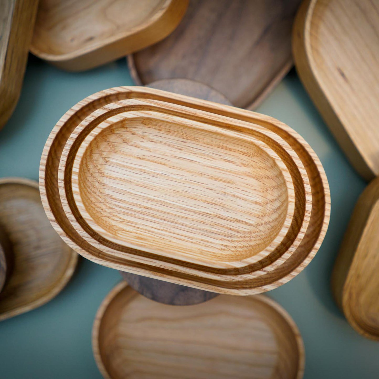 The Thing Spots, by Biglow Woodcraft; a wooden tray set for small objects. Various set of Thing spots on a green table. Hardwood White oak